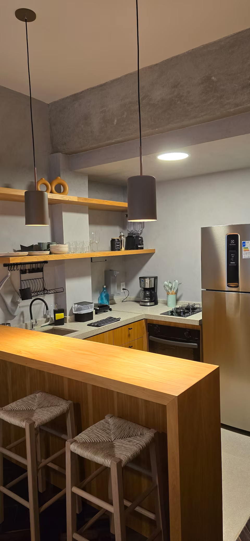 Cozinha completa em loft em Copacabana, com armários planejados em madeira clara, bancada e eletrodomésticos modernos.